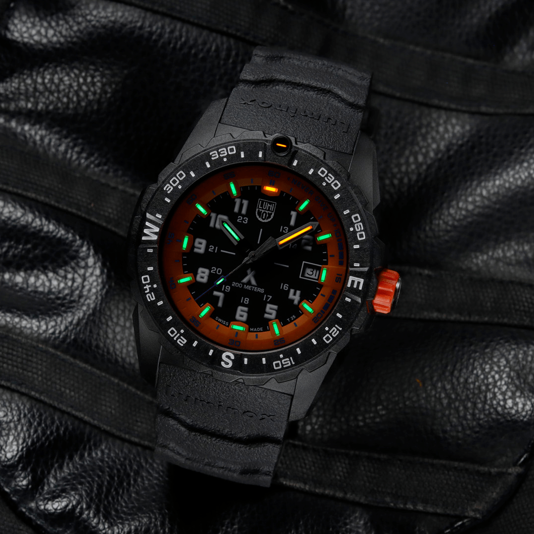 Rugged black wristwatch with colorful luminous markings on the dial and an orange crown.
