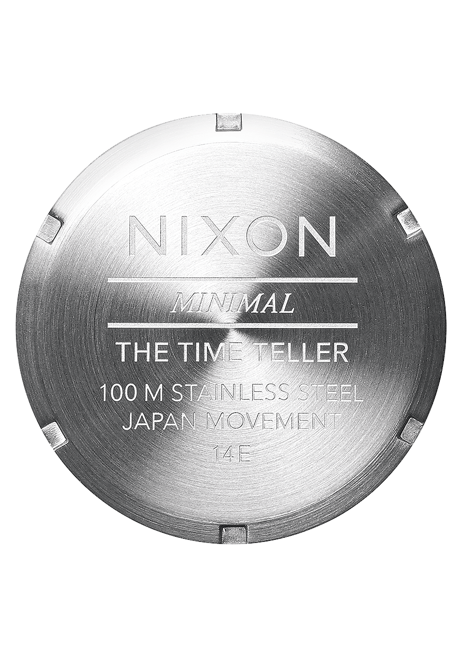 Circular metal watch case back engraved with ’Nixon’ and product details.