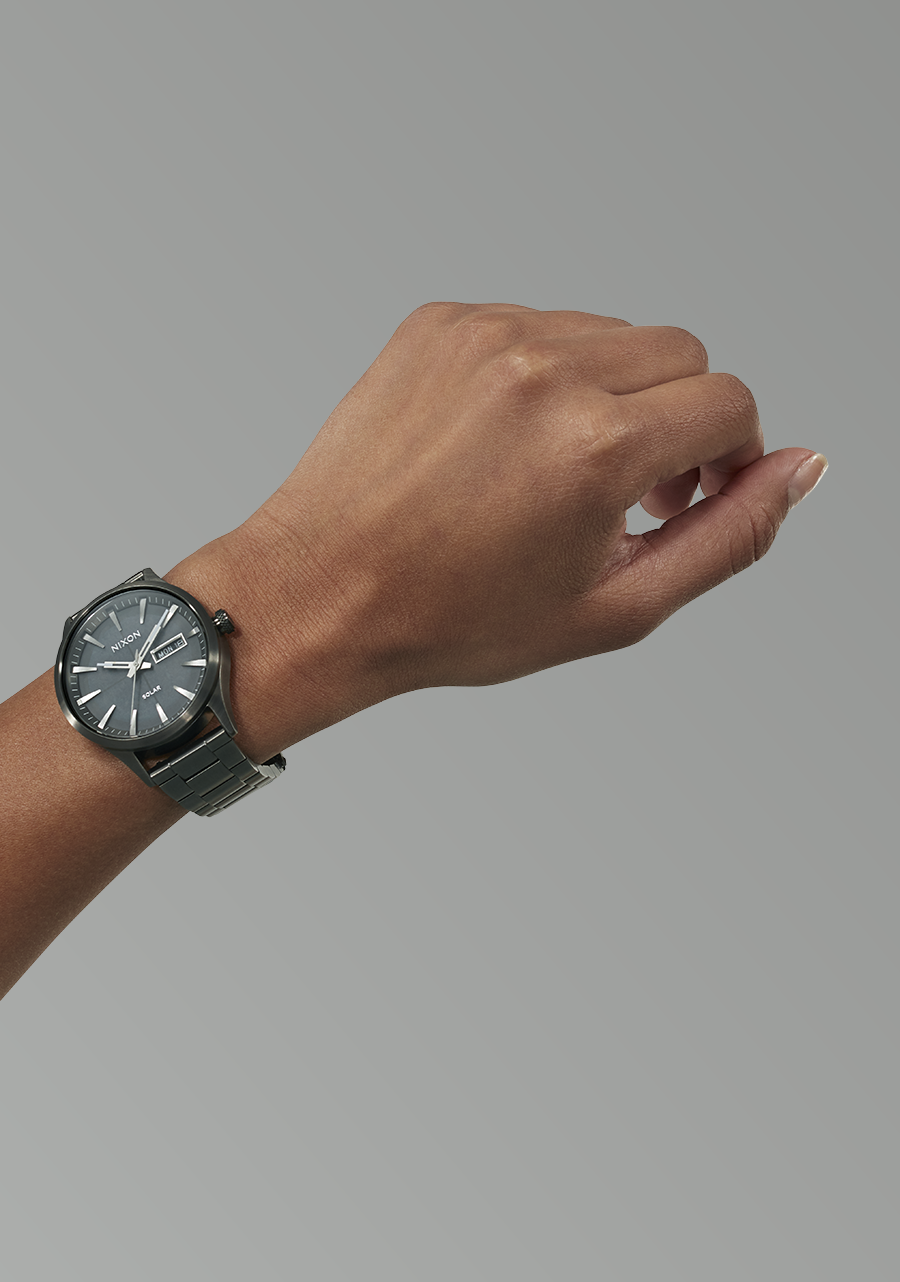 Wristwatch with a dark face and metal band worn on a person’s wrist.