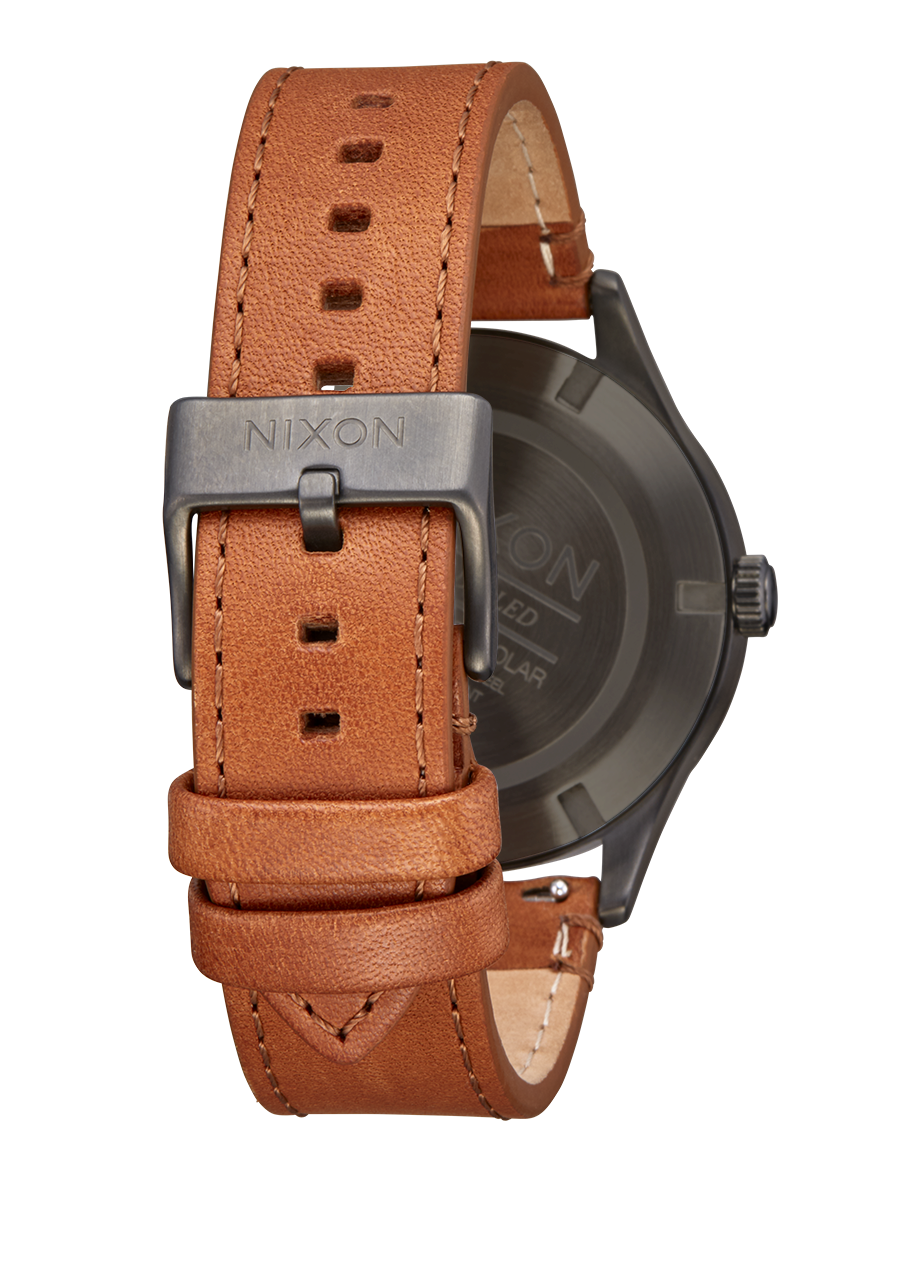 Brown leather watch strap with a metal buckle labeled ’Nixon’.