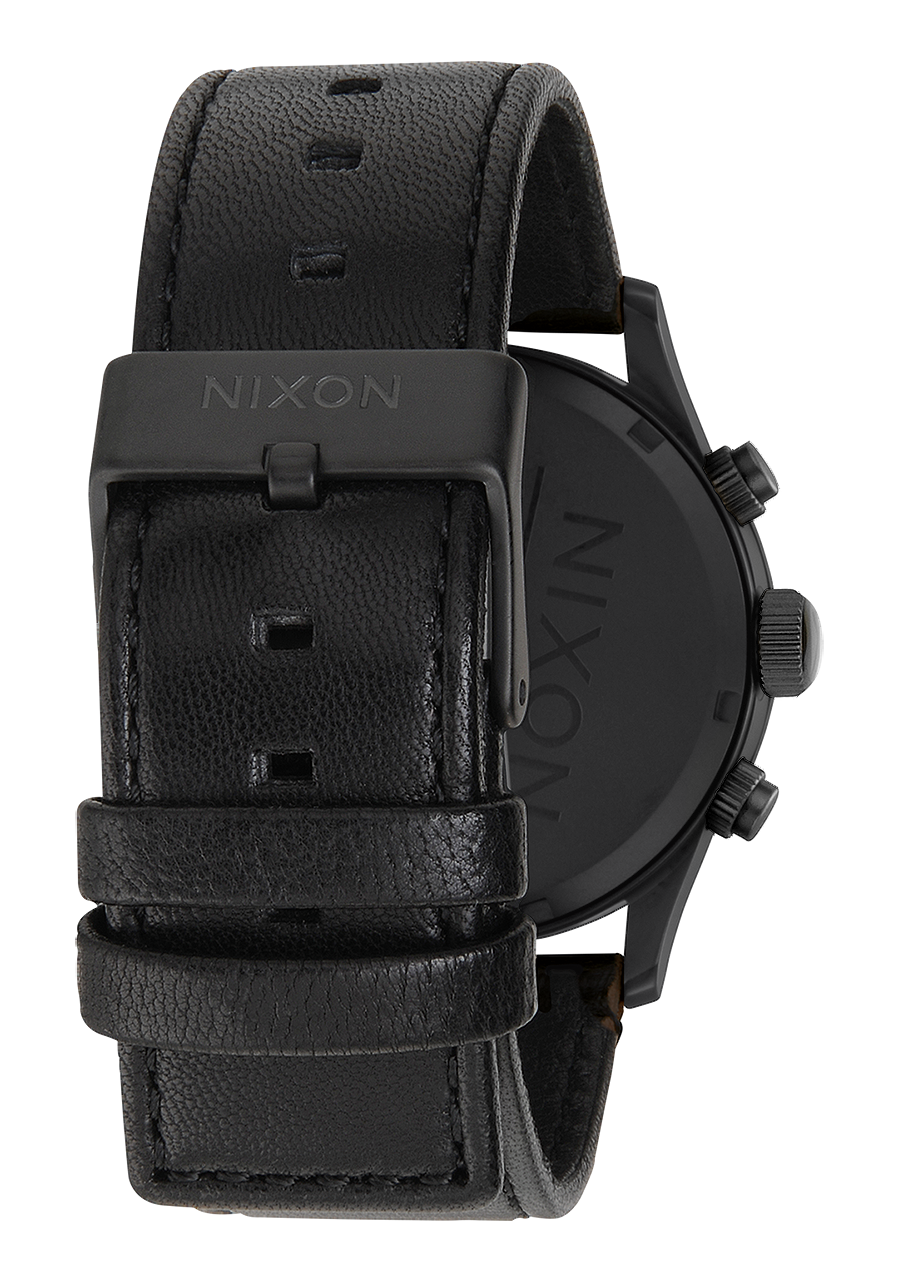 Black leather wristwatch with a chunky case and ’NIXON’ branding on the strap.