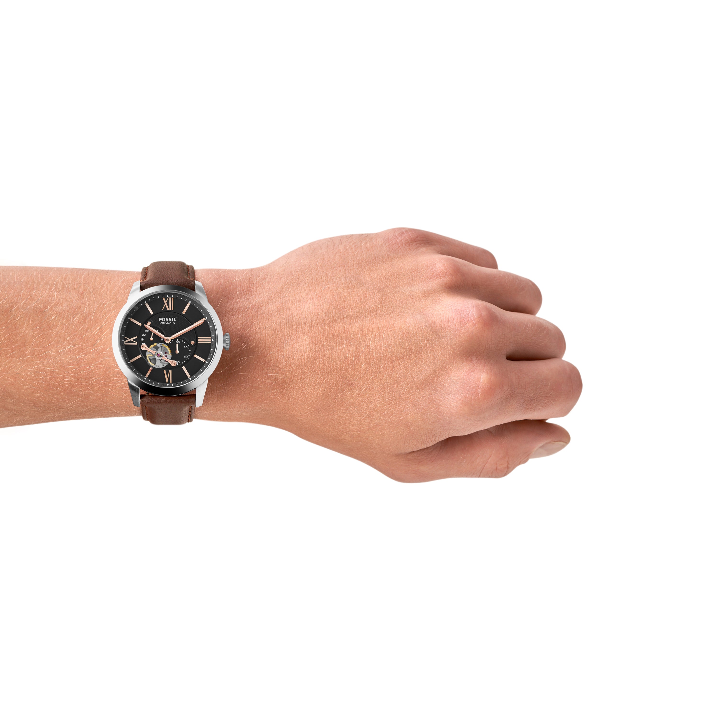 Wristwatch with a brown leather strap and black dial on a person’s wrist.
