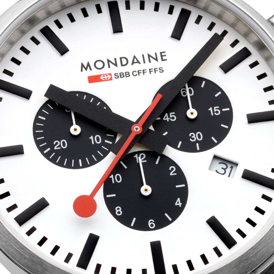 Mondaine analog watch face with chronograph subdials and a red second hand.