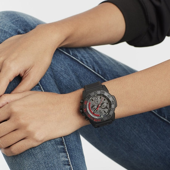 Sporty wristwatch with a black and red dial on a person’s wrist.