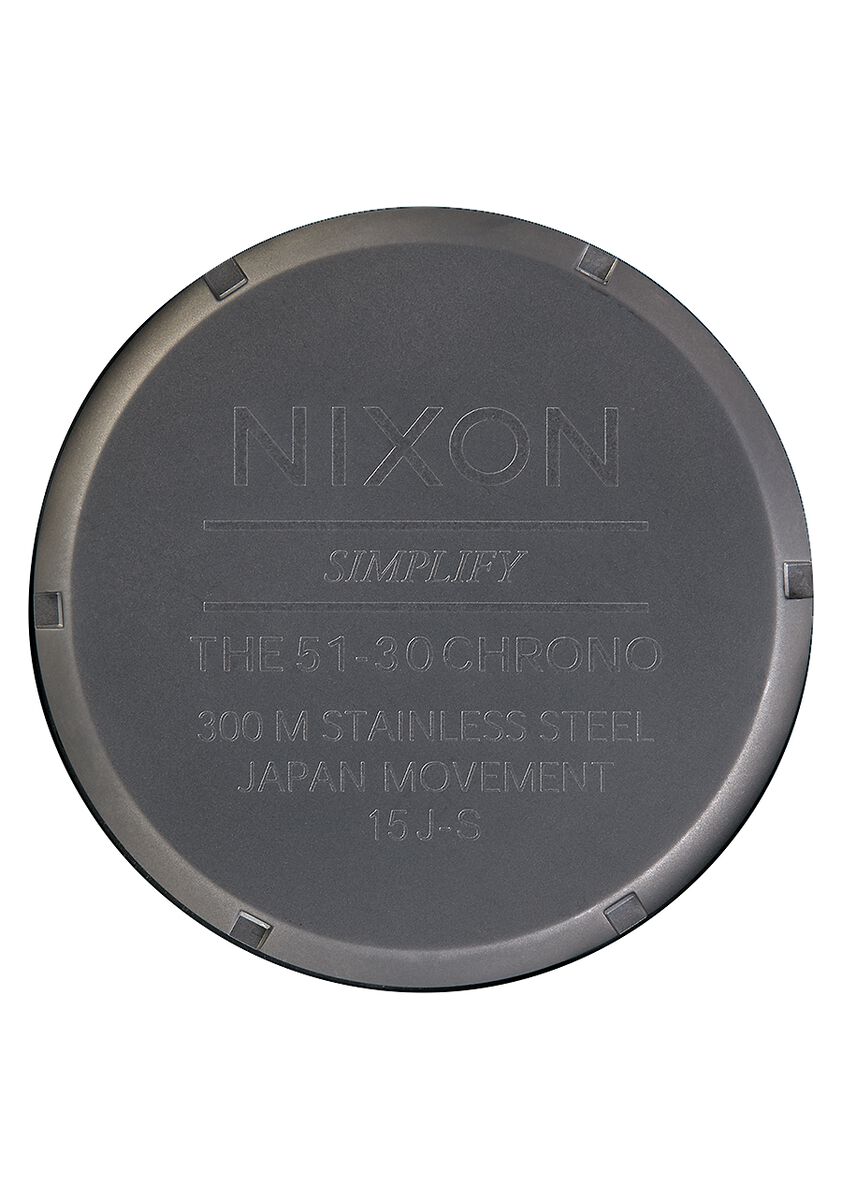 Circular metal watch case back with engraved text including the brand name ’Nixon’.