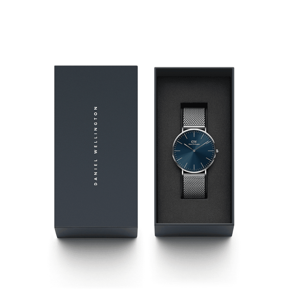 Elegant wristwatch with a blue face and mesh metal band in a presentation box.