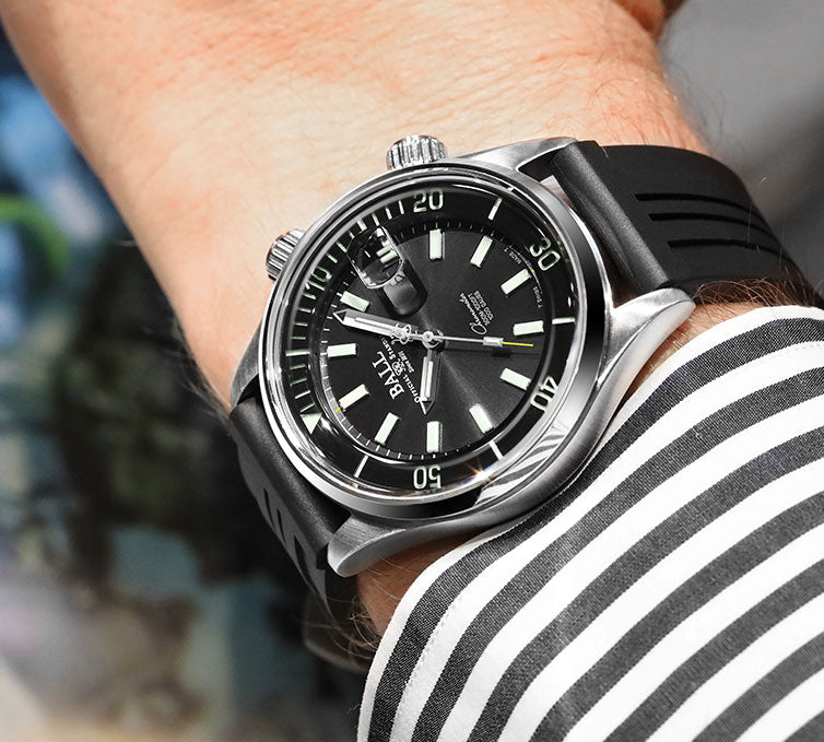 Stylish diver’s watch with a black dial and rubber strap worn on a wrist.