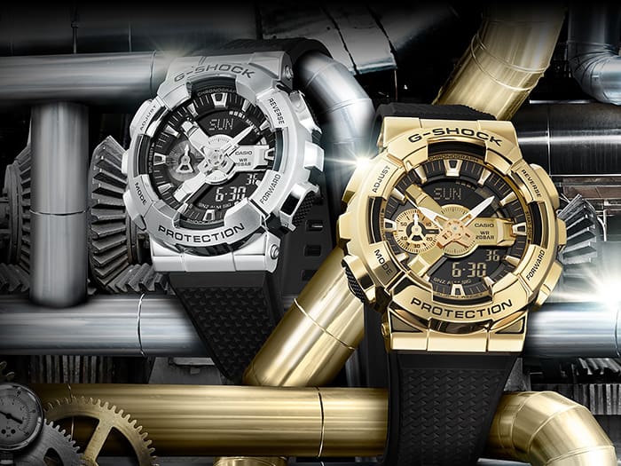 Two rugged G-Shock watches, one in silver and one in gold, with prominent digital-analog displays and chunky designs.