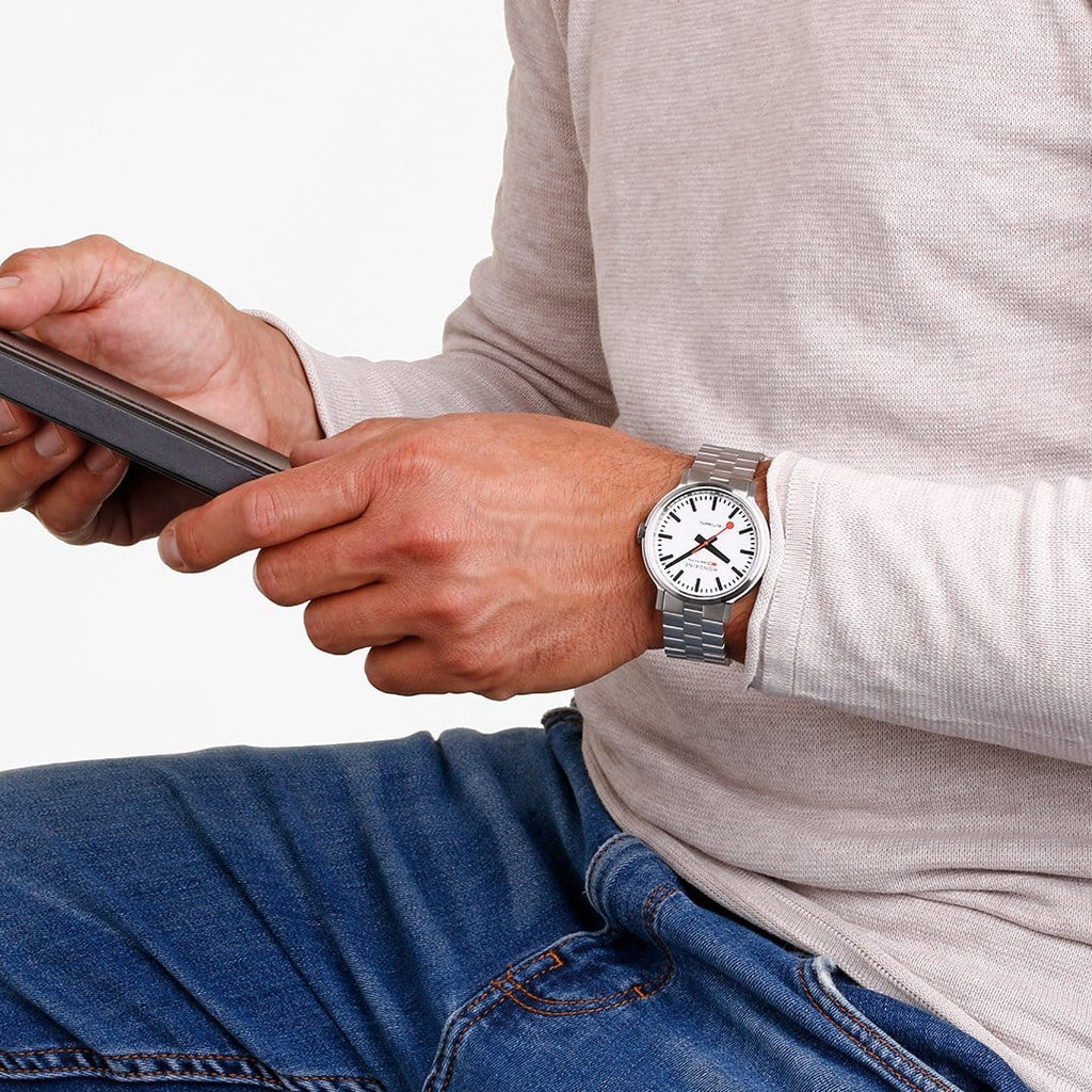 Wristwatch with a round face and metal bracelet on a person’s arm.