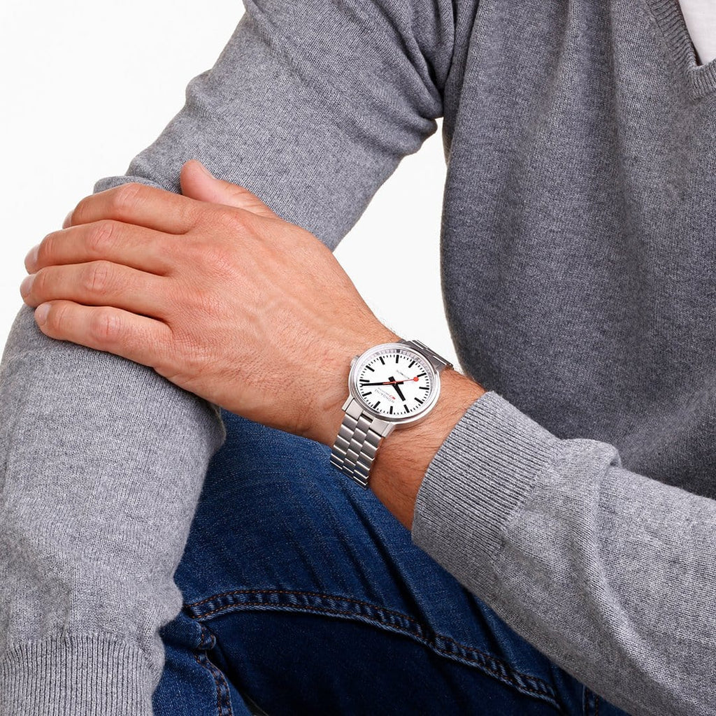 Wristwatch with a white face and metal bracelet worn on a person’s arm.