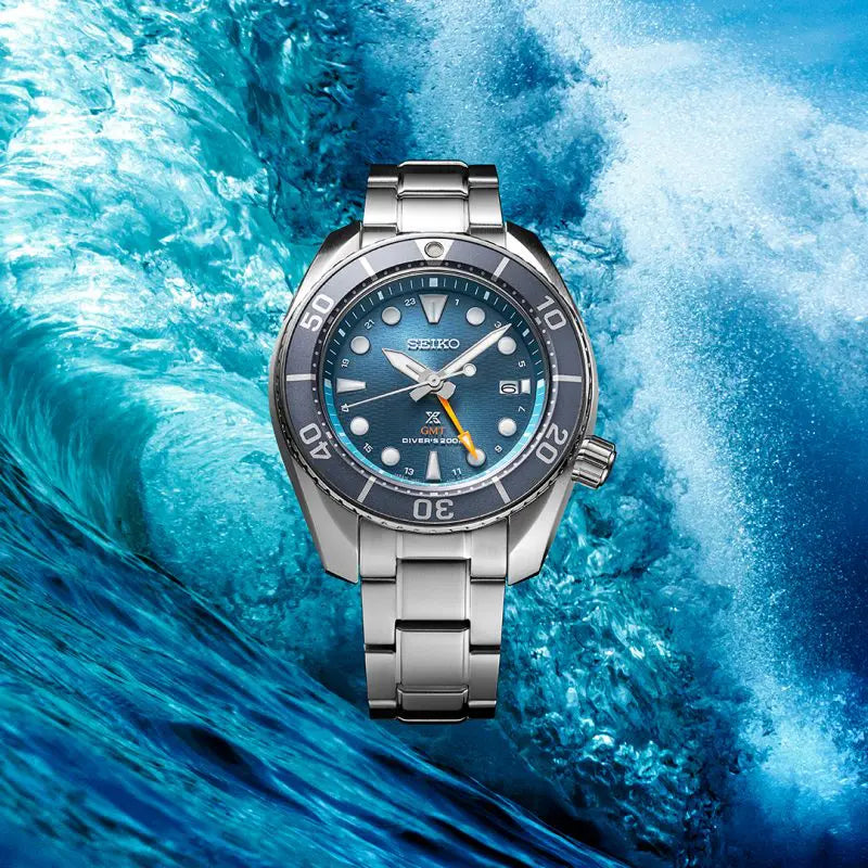 Stainless steel dive watch with a blue dial and bezel against a wave backdrop.