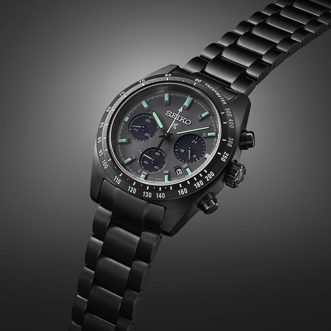 Black metal chronograph wristwatch with a dark dial and luminous markers.