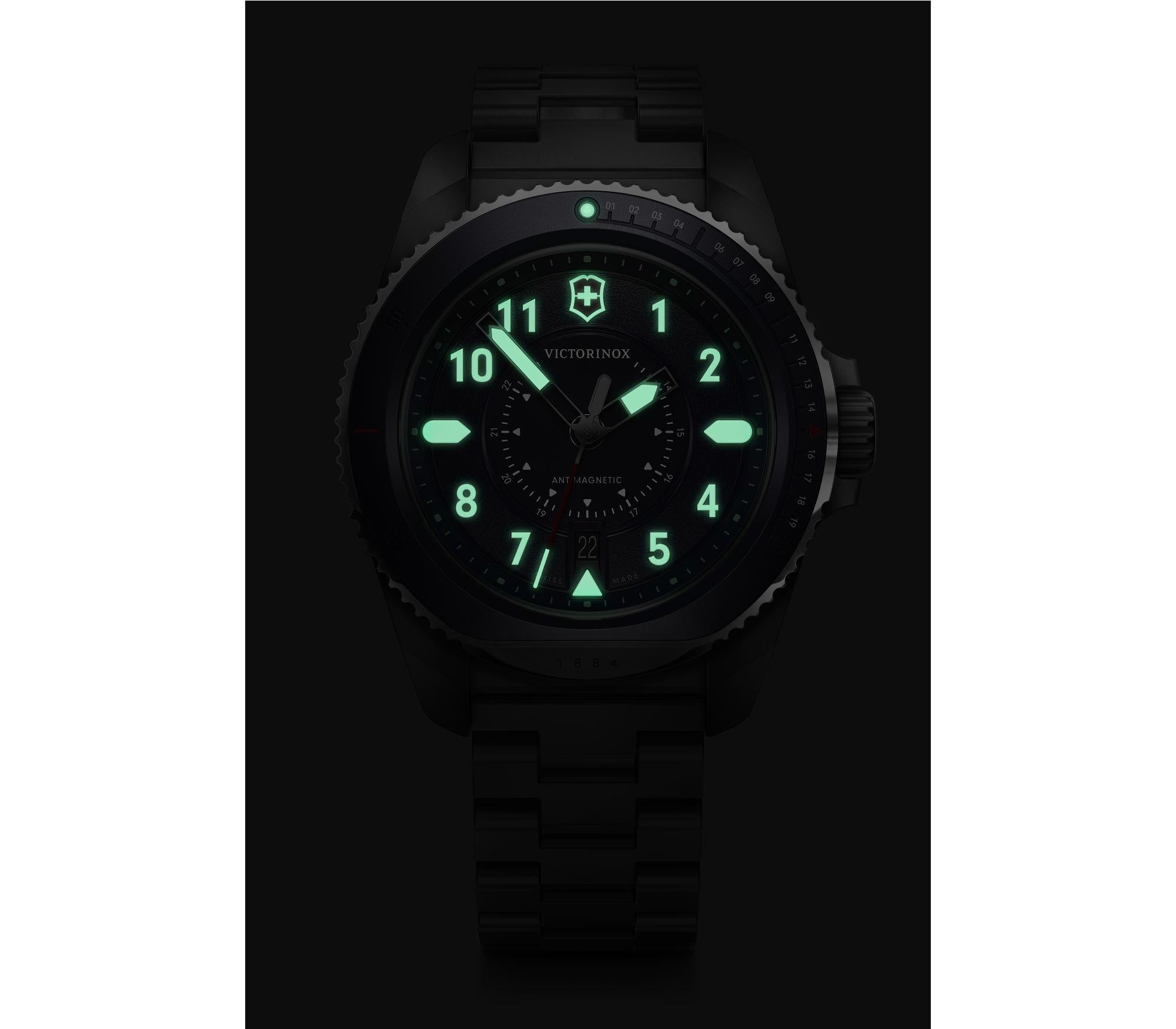 Luminous analog watch face with glowing green numbers and markings in darkness.