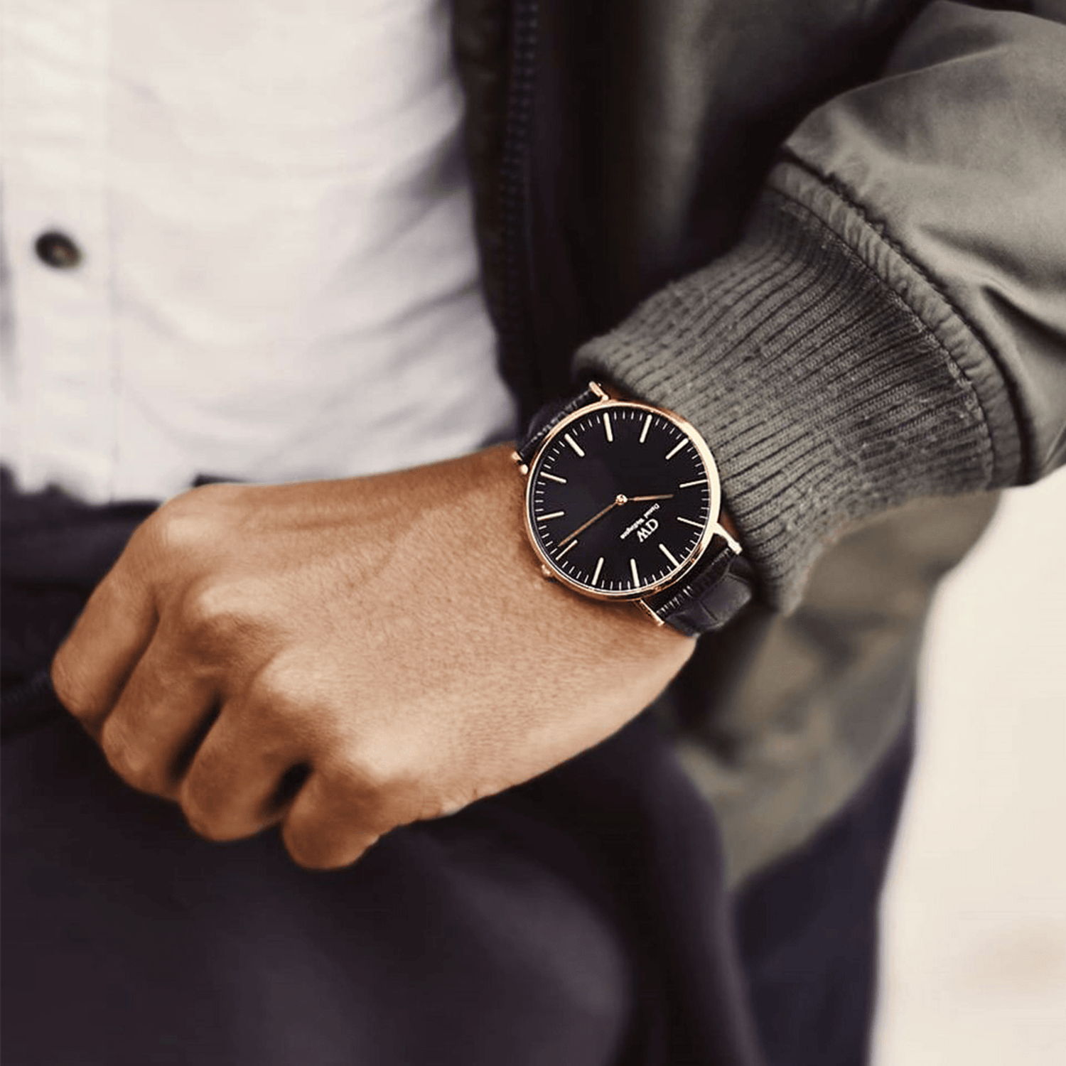 Elegant wristwatch with a black face and gold-tone case on a person’s wrist.