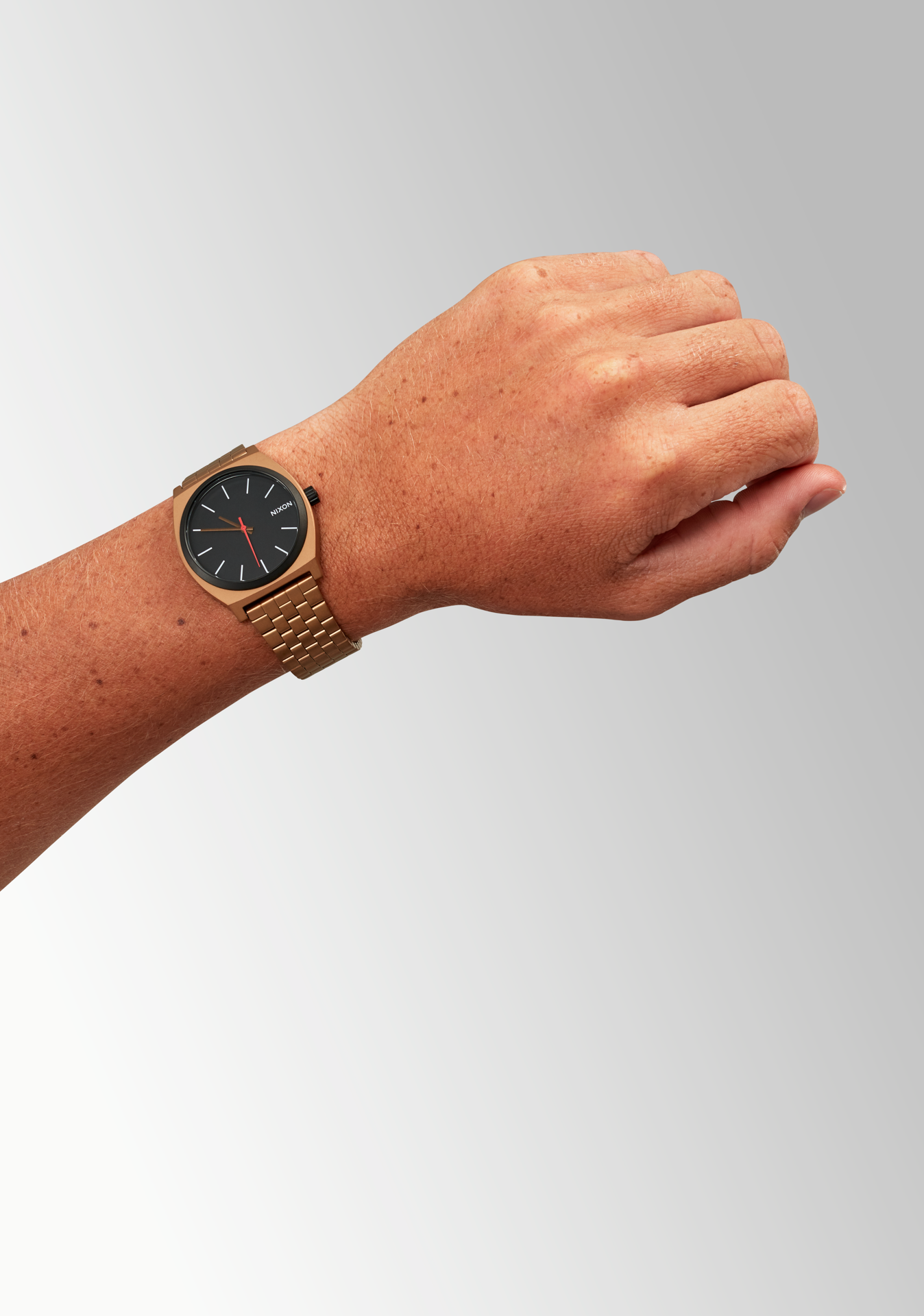 Gold wristwatch with a black face worn on a person’s wrist.