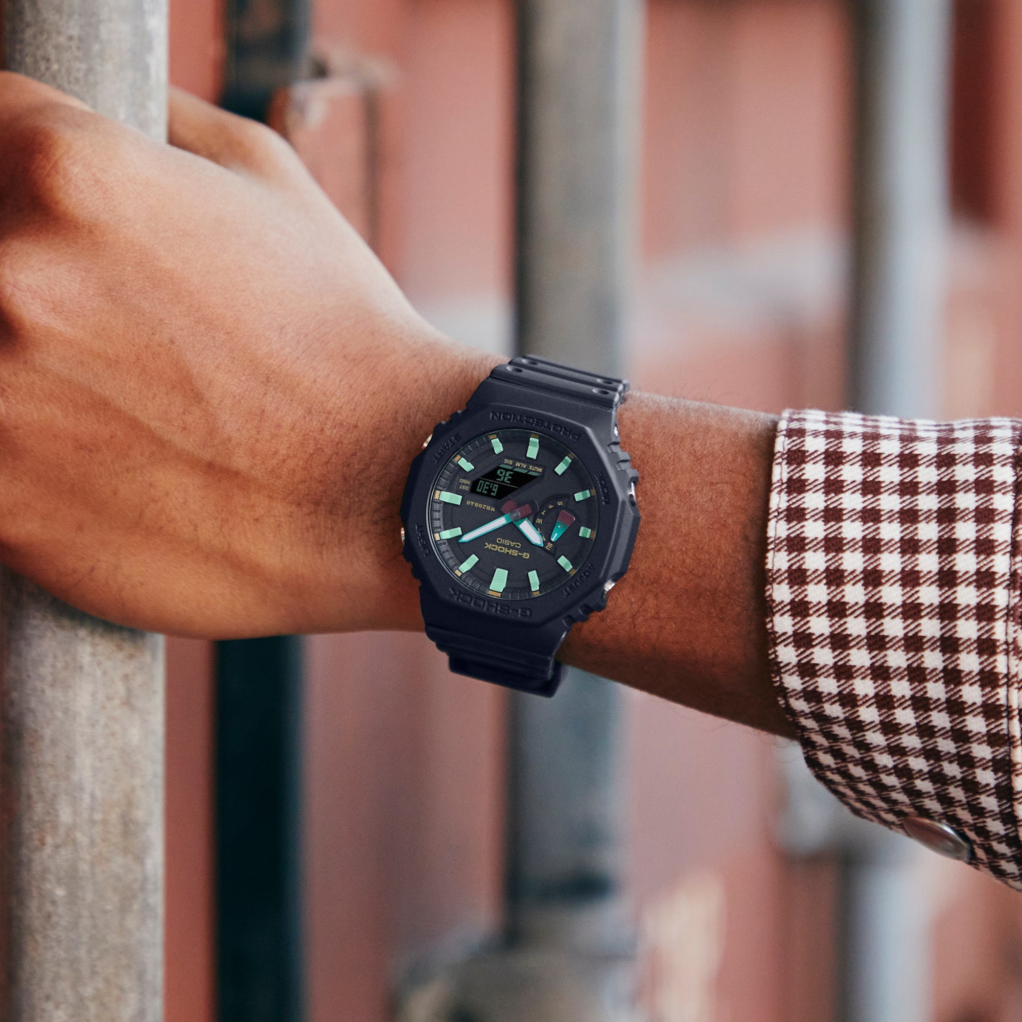 Black sports watch with green accents on the dial worn on a wrist.