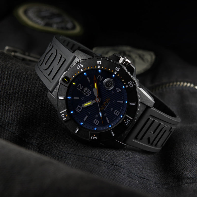 Sleek black wristwatch with a luminous blue dial and textured rubber strap.