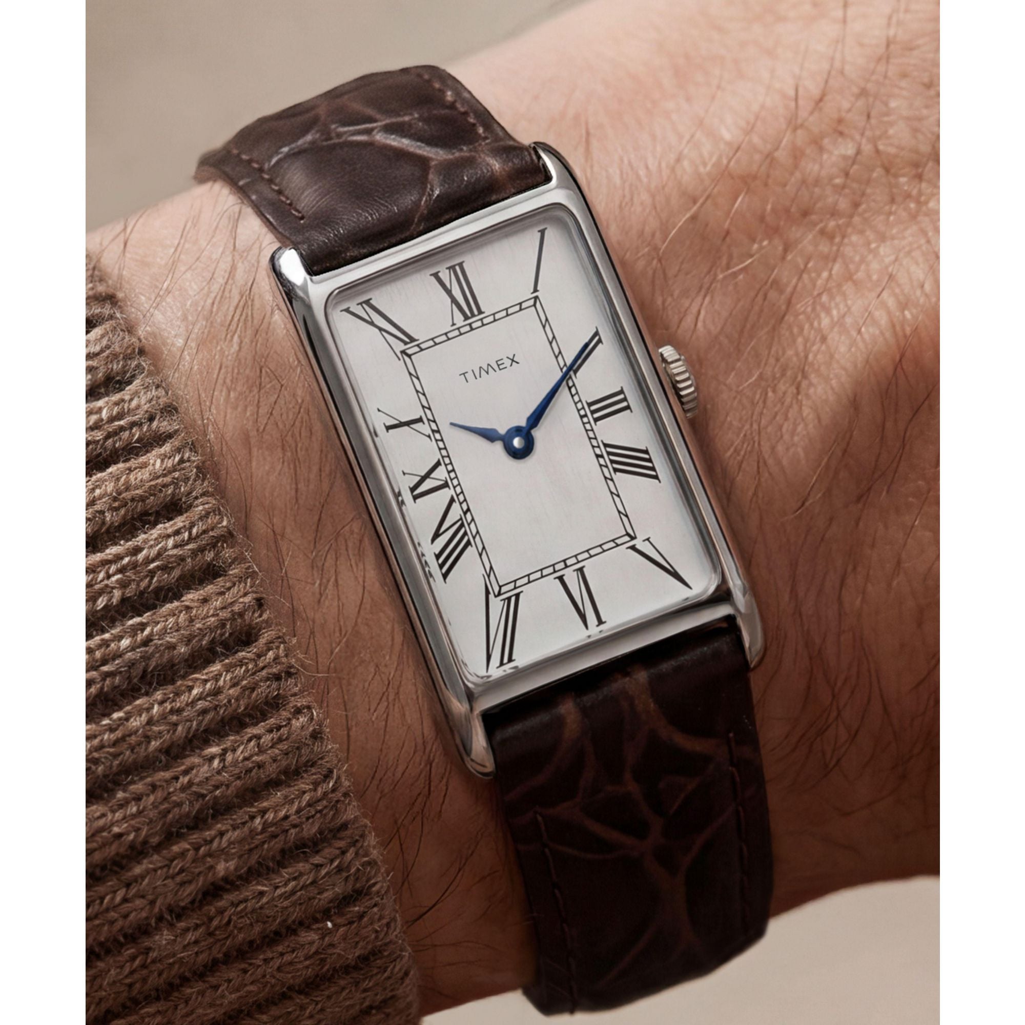 Timex 1976 Lexington TW2Y88200 silver dial with Roman numerals on a brown leather strap, worn on the wrist