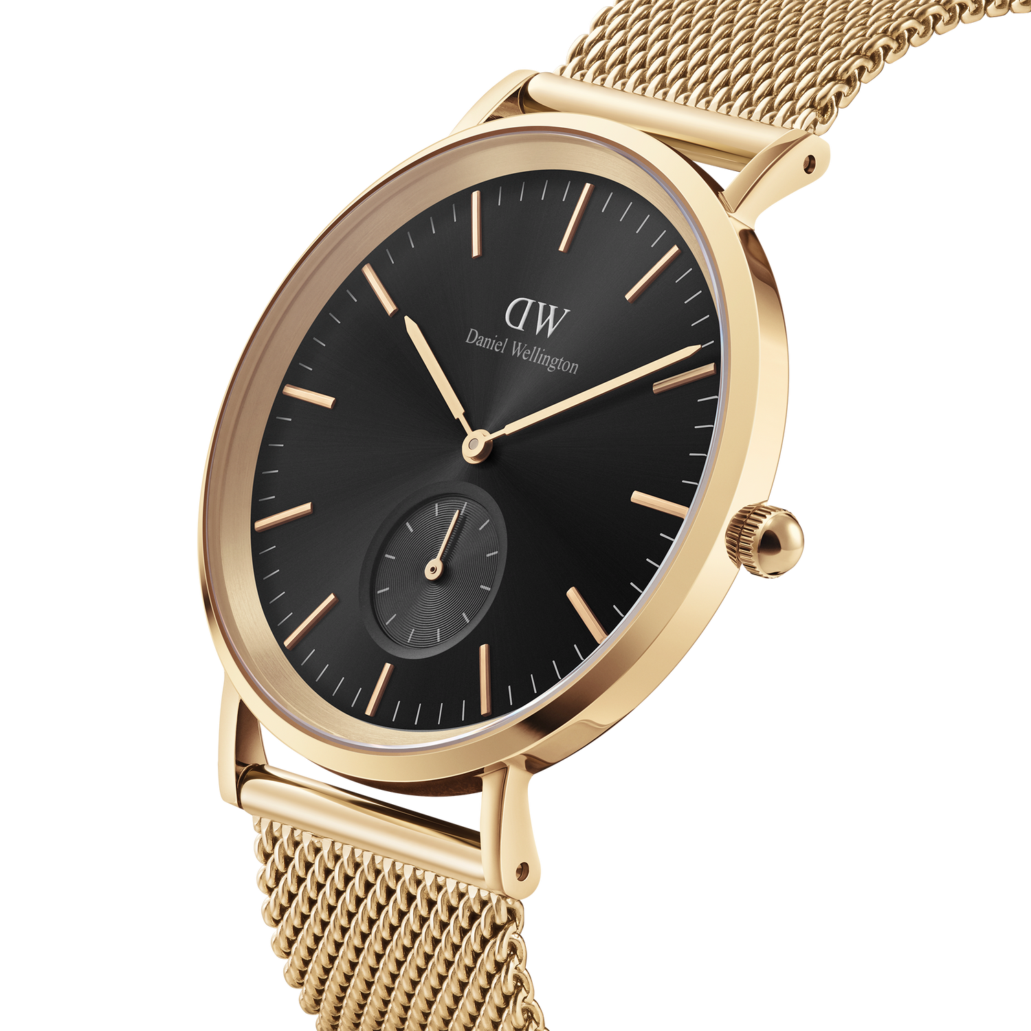 Gold-toned wristwatch with a black dial and mesh metal band.