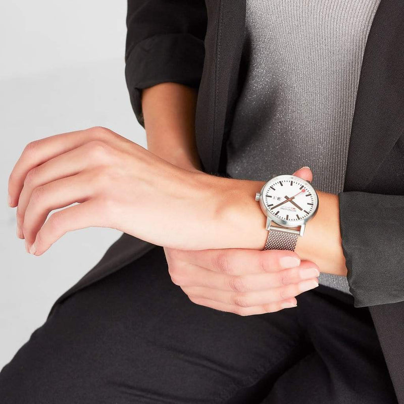 Wristwatch with a white face and silver mesh band.