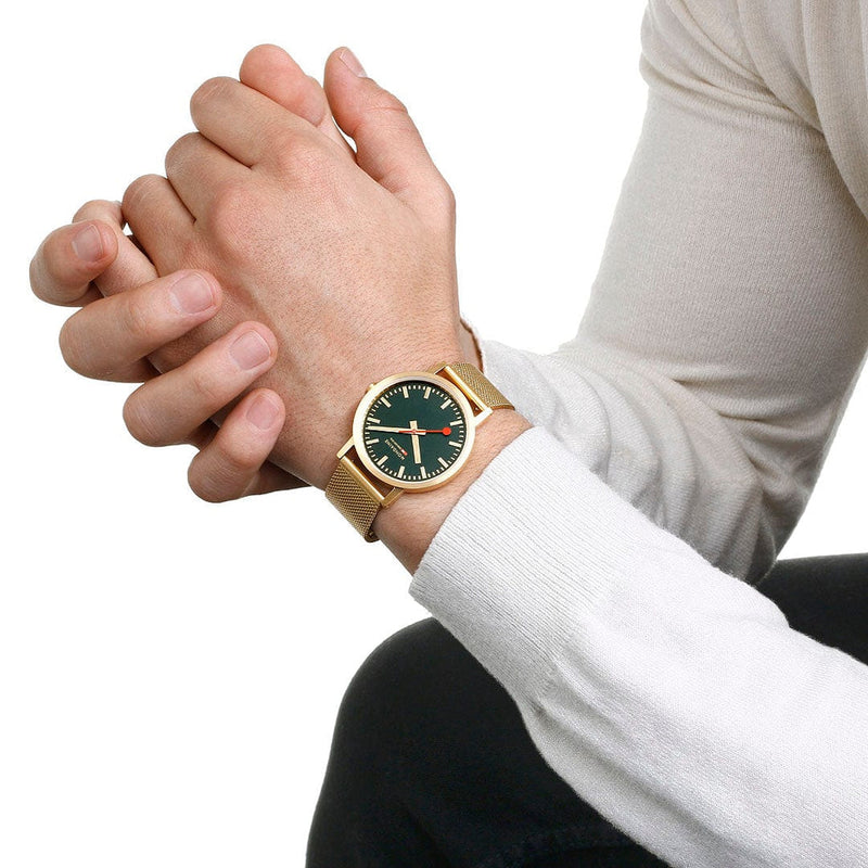 Gold wristwatch with a green dial face.