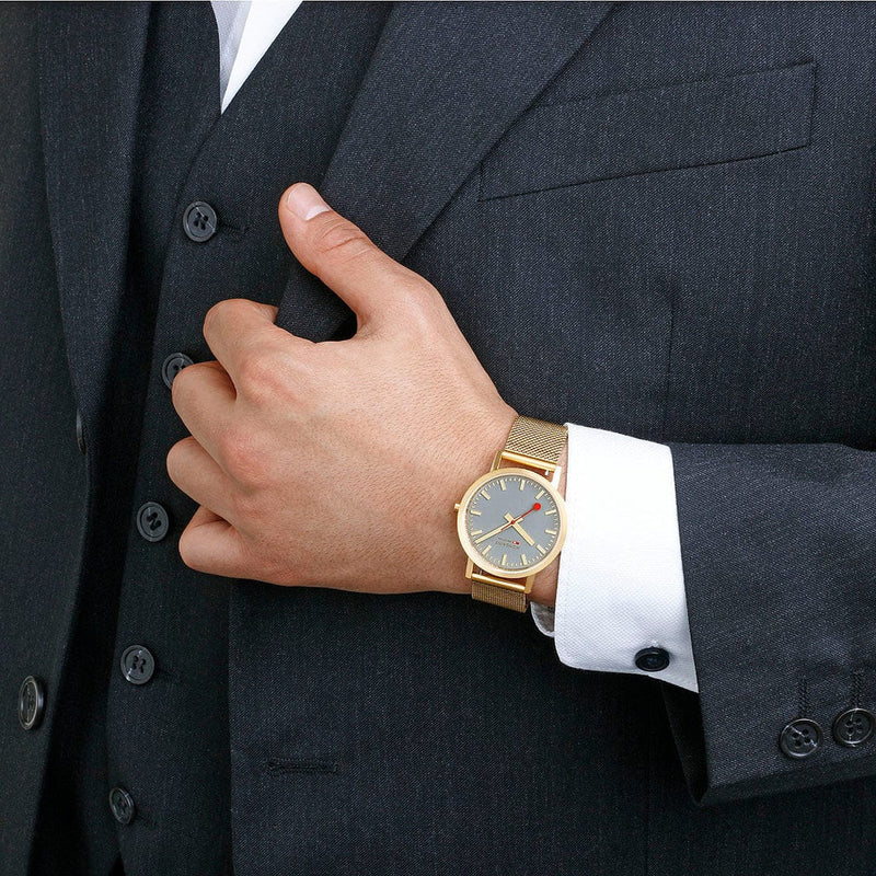 Gold wristwatch with a mesh band and blue dial face.