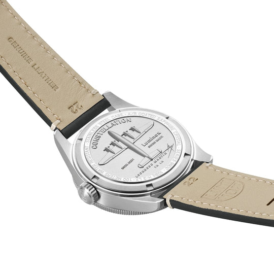 Wristwatch with a light-colored leather strap and silver-toned case, showing its engraved caseback.