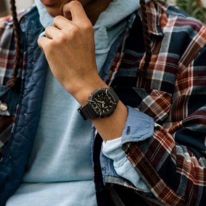 Wristwatch with a black face and strap worn on a person’s wrist.
